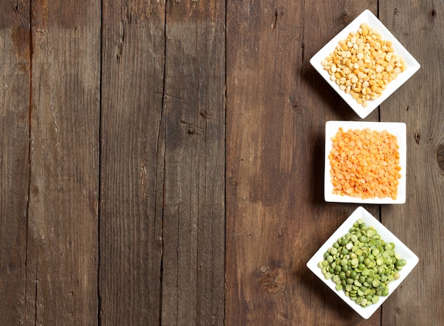 Legumes in bowls on a wooden table top view with copy space