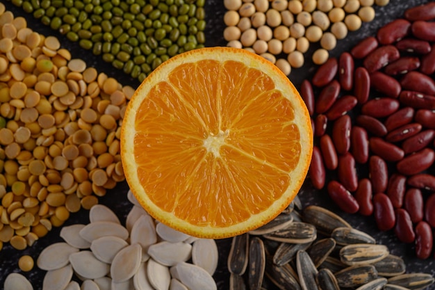 legumes with Orange cut in half on a black cement floor background