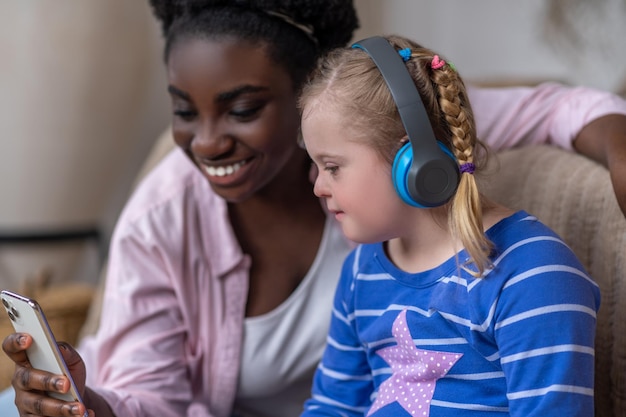 Leisure. A girl in hedphones sitting on the sofa with a woman