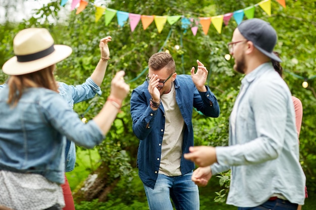 leisure, holidays, fun and people concept - happy friends dancing at summer party in garden