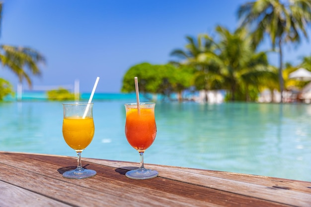 Leisure lifestyle poolside fruit cocktails served cold, blurred swimming pool palm trees, sunny view