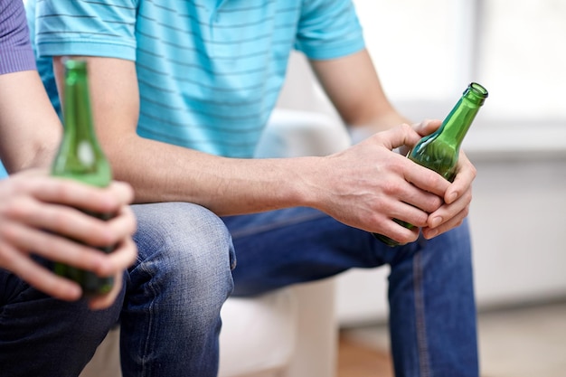 Photo leisure, people and alcohol concept - close up of male friends drinking beer at home