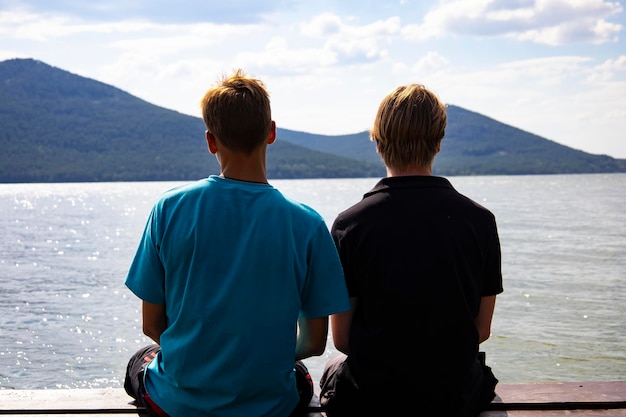 leisure and people concept - happy friends fishing and eating sandwiches on pier at sea.