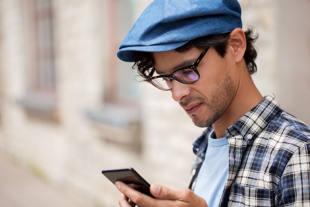 leisure, technology, communication and people concept - close up of hipster man texting message on smartphone