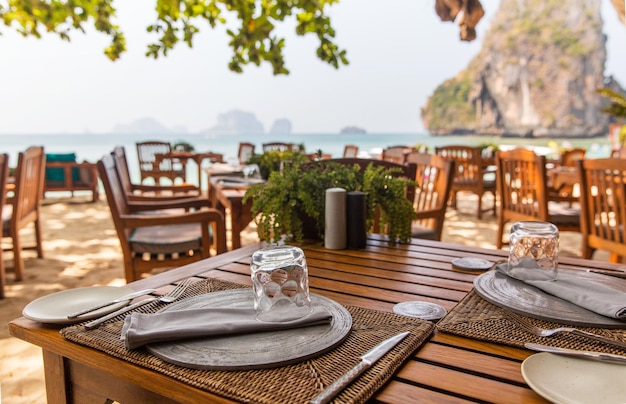 leisure, travel and tourism concept - close up of table setting at open-air restaurant on beach