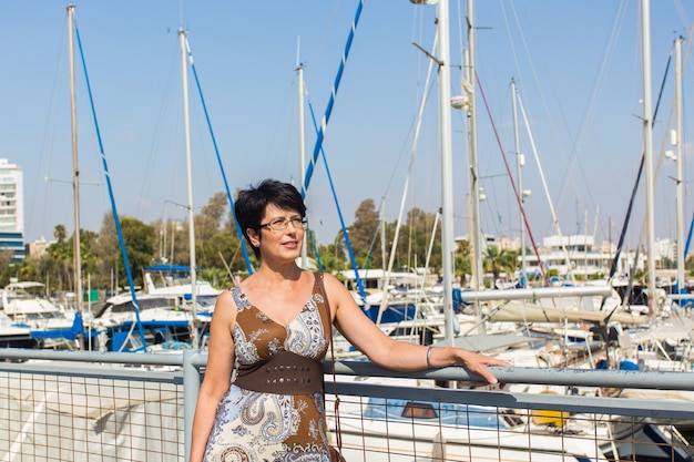 Leisure woman on holiday near yacht and sailboats marina resort town. Luxury lifestyle.