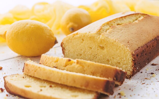 Lemon cake with fruits on white wooden surface