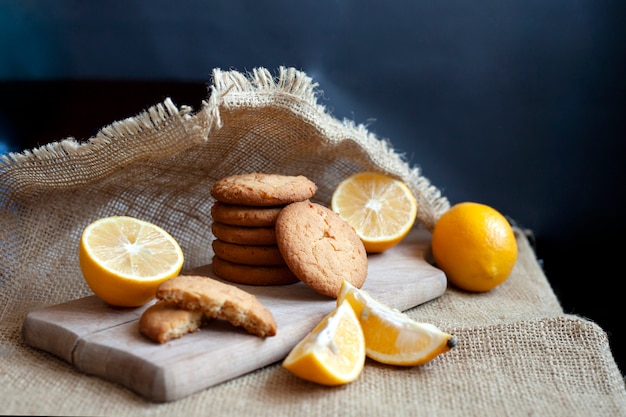 Lemon gingerbread cookies lie on a wooden board on a rustic table, still life of fresh biscuits with citrus, copy space