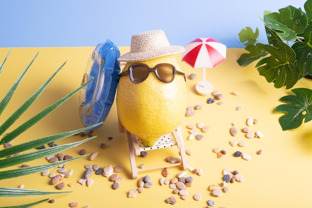 Lemon in a hat and sunglasses with an inflatable circle on a sun lounger on the beach