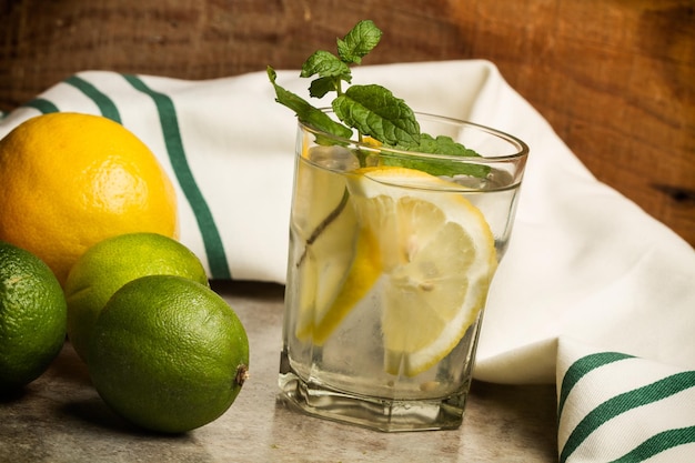 Lemon limes and a glass of lemonade on a marble counter