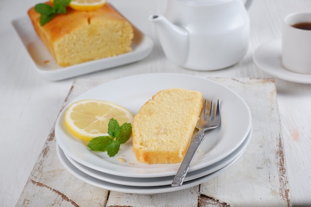 lemon pound cake with white teapot and a cup of coffee with blury backgroundwhite background