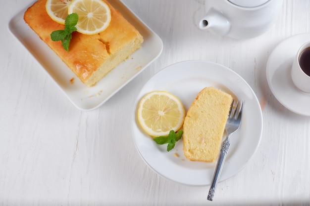 lemon pound cake with white teapot and a cup of coffee with blury backgroundwhite background