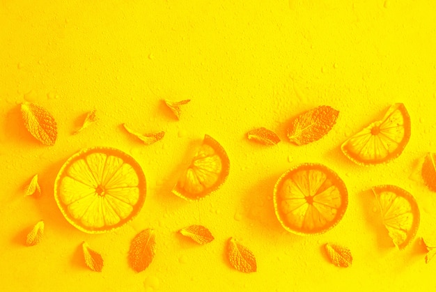 Lemon slices and mint herbs against yellow with copyspace.