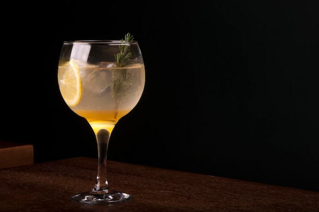 lemon tropical cocktail glass with rosemary gin and ice in front view wooden table