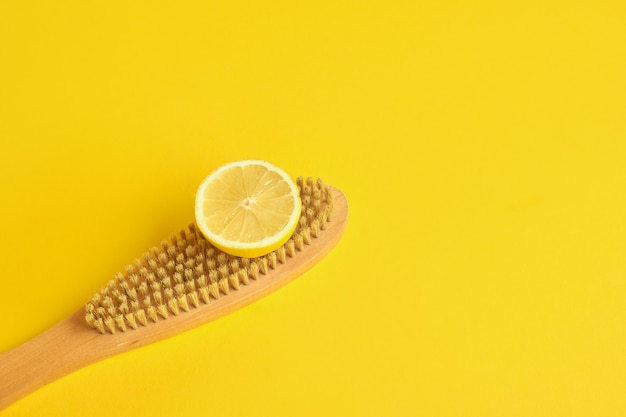 lemon and wooden brush on yellow background