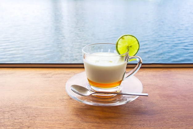 Lemon yogurt fresh milk in a clear glass placed on a brown wooden table with sea water surface.