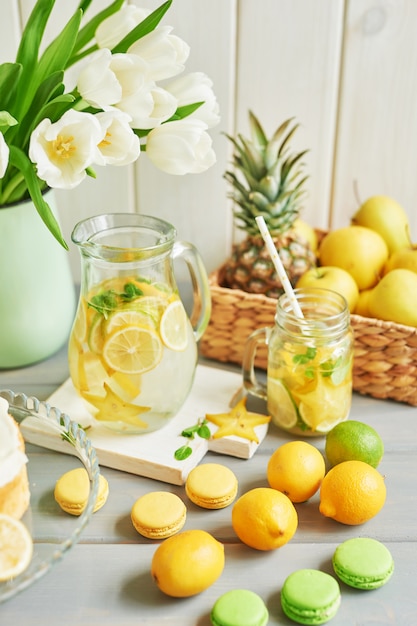 Lemonade, fruits, sweet macarons and tulip flowers