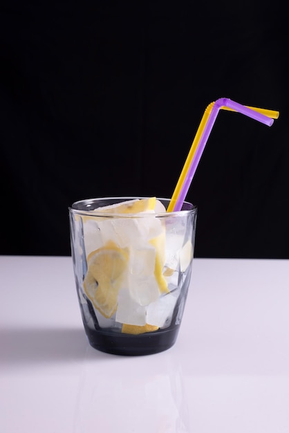 Lemonade in a glass with a straw on a white table and black background Minimalist