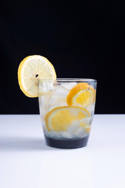 Lemonade in a glass with a straw on a white table and black background Minimalist