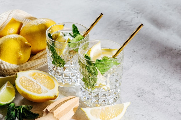 Lemonade on glasses and lemons and limes on white market bag on marble background