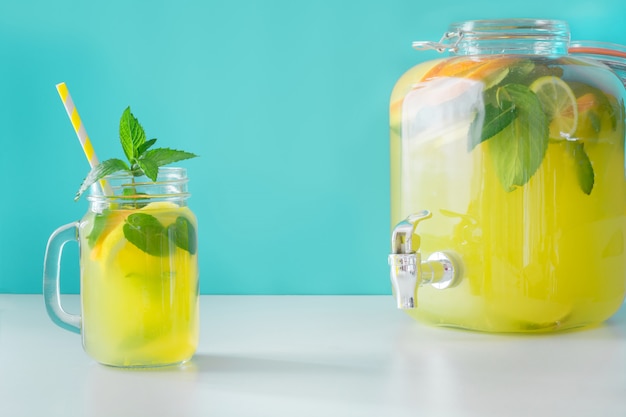 Lemonade in mason jar with lemon and mint on blue. Copy space.