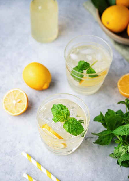 Lemonade soda drink with fresh lemons Refreshing cocktail with lemon mint and ice on blue background Summer cold drinks concept Top view