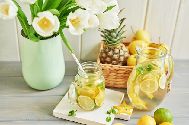 Lemonade, sweet macarons, fruits and tulip flowers