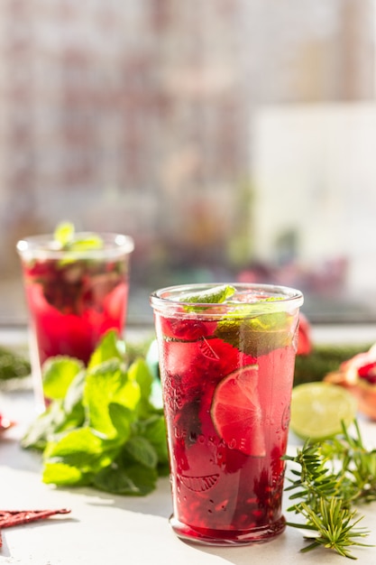 Lemonade with pomegranate and lime in glass in the sun with shadow