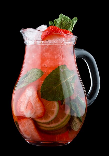 Lemonade with strawberries and mint in glass jug on black background