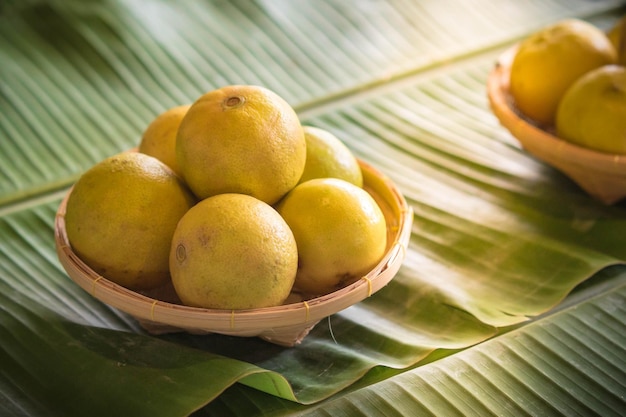 Lemons in basket weave on green banana leaf Healthy fruits background