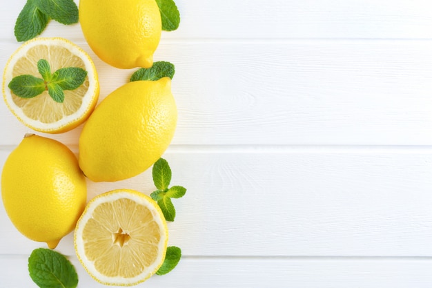 Lemons and mint on white wooden background.