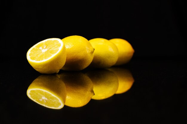 Lemons in a row on a black reflected surface