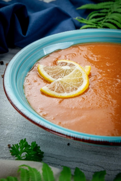 Lentil cream soup with lemon slices in a plate on a light table