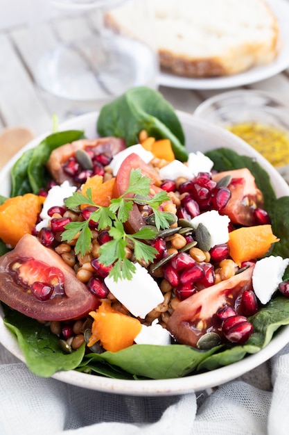 Lentil salad with pumpkin tomatoes pomegranate seeds spinach and goat cheese