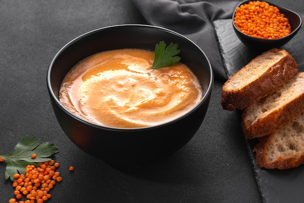 Lentil soup with red lentils whipped into a puree with cream on a dark background top view