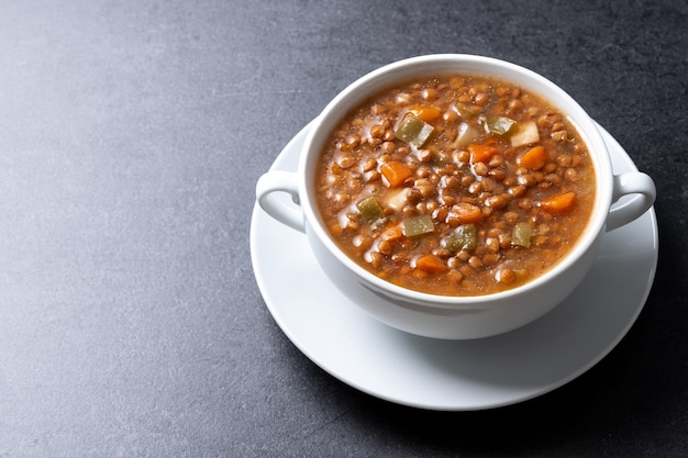 Lentil soup with vegetables in bowl isolated on white background