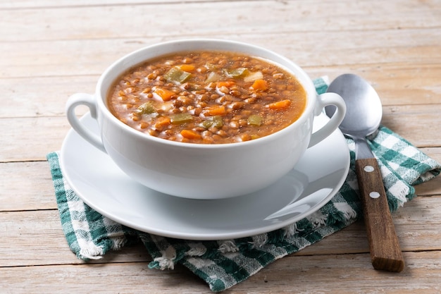 Lentil soup with vegetables in bowl on wooden table