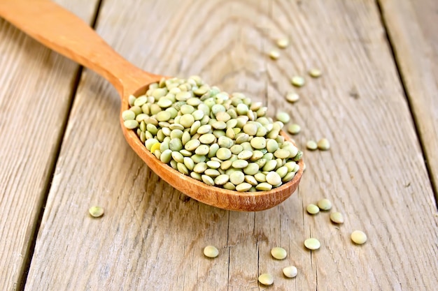 Lentils green in wooden spoon on board