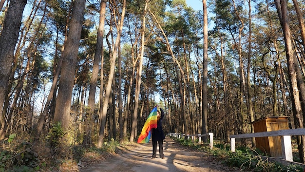 Lesbian bisexual woman girl holding a rainbow LGBT flag and a walk along the trail in the forest in the month of pride and celebrating a gay parade Bisexuality Day or National Coming Out Day