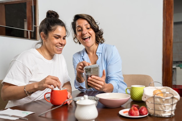 lesbian couple having breakfast and checking the cell phone