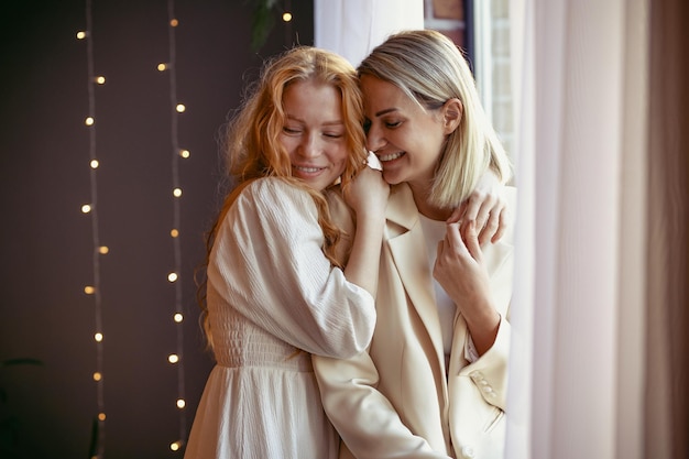 Lesbian couple having dinner in a restaurant. One girl hugs her beloved whispering in her ear