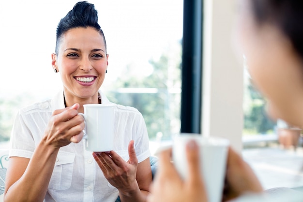 Lesbian couple smiling while having a cup of coffee