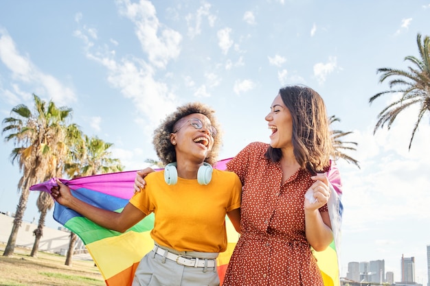 Lesbian loving couple looking at each other with rainbow flag concept of pride homosexual equality f...