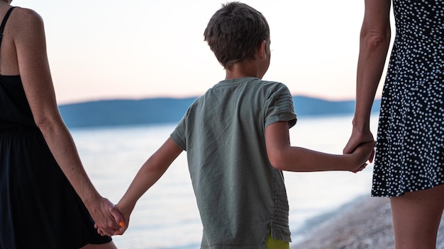 Lesbian mothers and their son walking on the beach