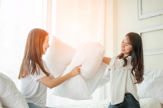 Lesbian women at pillow fights in bedroom.