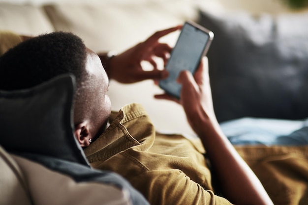 Let me engage in some chats here Cropped shot of an unrecognizable man using a smartphone while relaxing on his couch at home