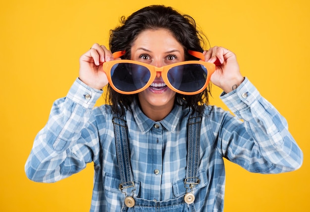 Let me see the party girl on yellow background joyful and charming smile student girl having fun Fashion portrait pretty young woman hipster woman in funny party glasses casual and denim trends