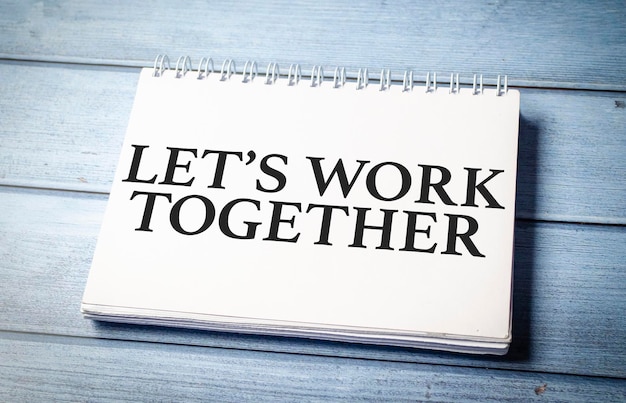 Let's work together word on notepad and blue wooden background