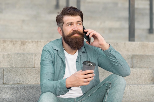 Lets communicate through call Hipster drink coffee talking on smartphone outdoors Phone conversation and communication Mobile communication Business communication Using communication technology