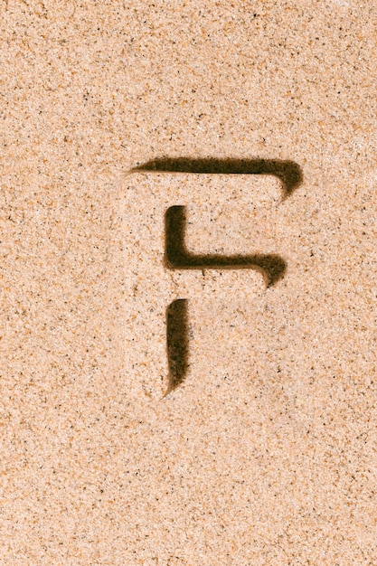 Letter F of the sand isolated on the beach sand concept of summer alphabet